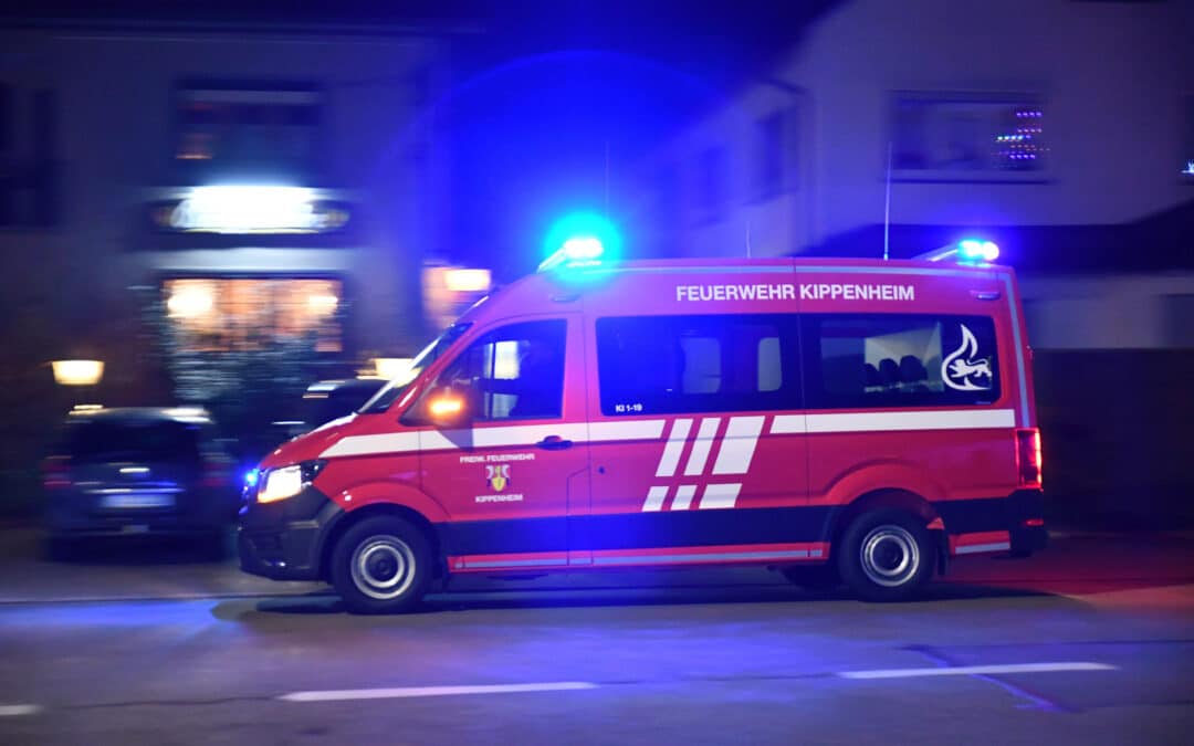 Ein rotes Einsatzfahrzeug der Feuerwehr Kippenheim mit Blaulicht fährt nachts schnell eine Straße entlang.